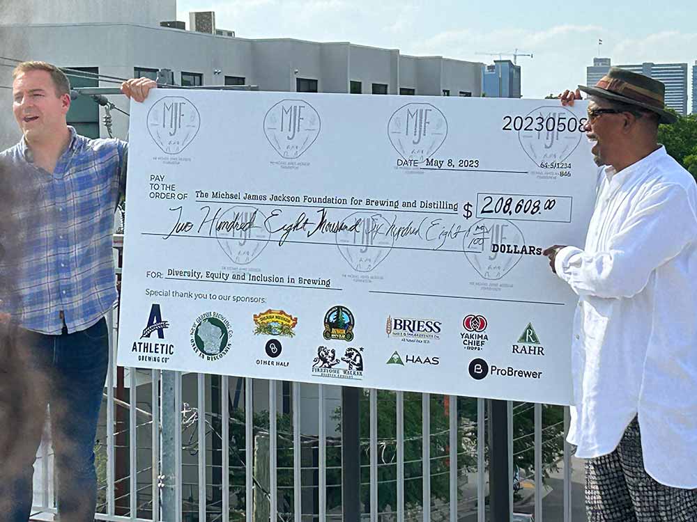michael james jackson foundation x probrewer check presentation with founder and chair garrett oliver and athletic co-founder bill shufelt